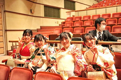 振り袖姿の女性4人が観客席に1列に並んで座っている写真