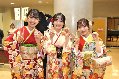 振り袖姿の女性3人が右手でピースサイン、左手で丸を作っている写真