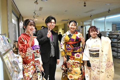 振り袖を着た女性3人とスーツを着た男性1人がピースサインしている写真