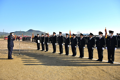 敬礼する1人の男性に向き合って1列に並んで立つ消防団制服姿の人たちの写真