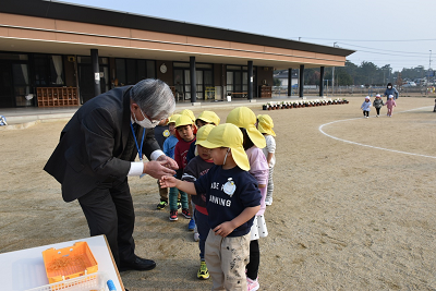 背をかがめて園児と話している男性の写真