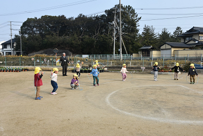 縄跳びをする園児を後ろから見ている男性の写真
