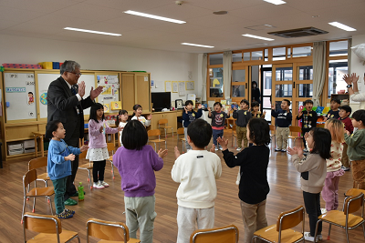 男性と園児達が輪になって手を叩いている写真