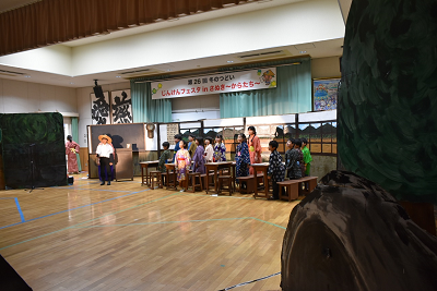 大勢の着物の人が机の横に立っている写真