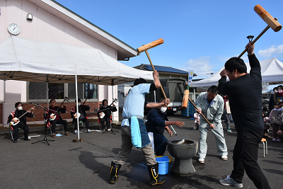 杵を持って餅をつく男性3人の写真