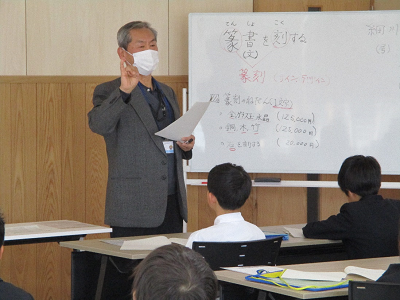 ホワイトボードの前で説明する男性の写真