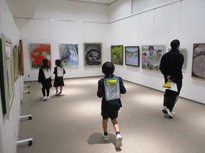 児童たちが壁に掛けられた絵画を見ている写真
