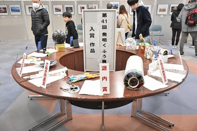 円形のテーブルに飾られた様々な作品を見る男性の写真