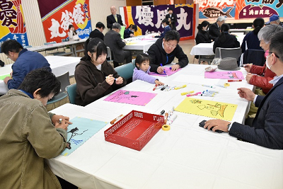 画用紙に絵を描く子供と大人の写真