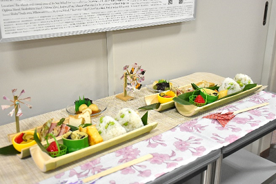 縦に切った竹を器におにぎりやおかずが盛られている写真