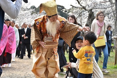 和装の男性が子供に紙吹雪を降らせている写真