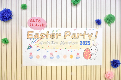 お花紙が飾られた壁に「イースターパーティー」と書かれた紙が貼られている写真