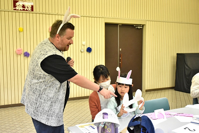 ウサギ耳のカチューシャをつけた男性と親子が話している写真