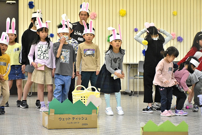 ウサギ耳を付けた子供たちが草の飾りがついた段ボールの前で並んでいる写真