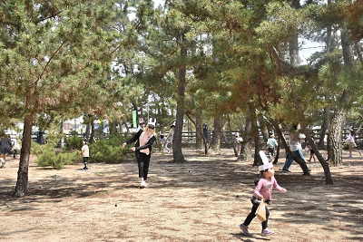 木々が生える広場でウサギ耳をつけて走る子供たちの写真