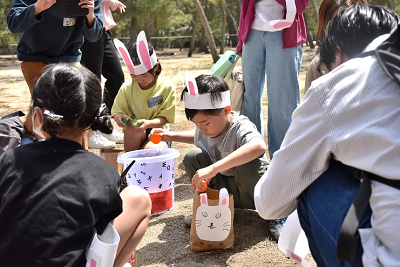 しゃがんでボールを別の容器に移動させている子供たちの写真