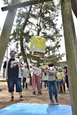 目隠しをした児童が吊り下げられた箱に棒を当てている写真