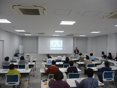 着席した人たちの前で男性が話している写真