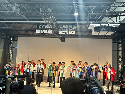 大勢の法被を着た人が食べ物を持ってカメラを持った人の前に立っている写真