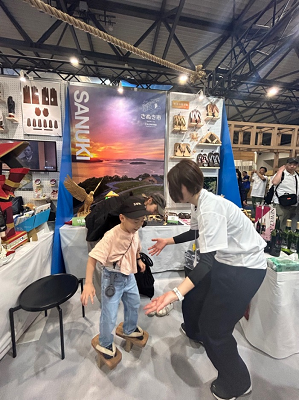 大きな下駄を履いた子供を支えようとする女性の写真