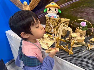 竹細工の風車に向かって息を吹きかけている子供の写真