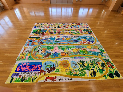 イラストが繋がっている5枚の絵が床に並べられている写真