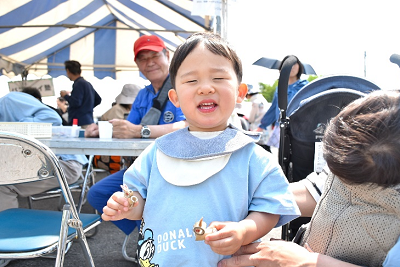 水色の服を着た男の子が竹の小物を持っている写真