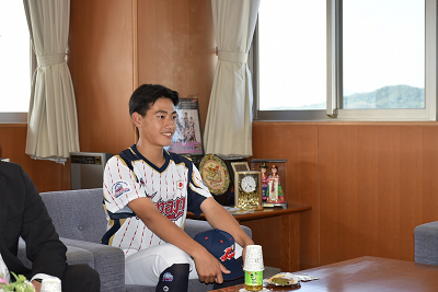 笑って座っているユニフォームを着た人の写真