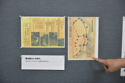 壁に貼られた展示物を指さしている写真