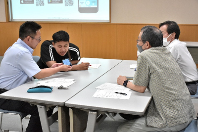 グループの1人がスマホに向かって話している写真