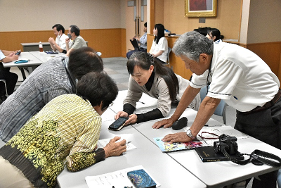 グループ全体にスマホを見せる女性の写真