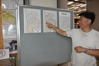 展示パネルに貼られた地図を指さしている男性の写真