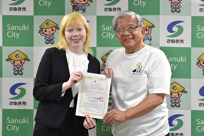 男性と金髪の女性が賞状を持っている写真