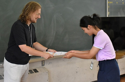 男性から紙を受け取る児童の写真