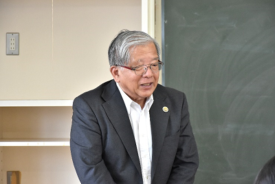 黒板の前で話している男性の写真