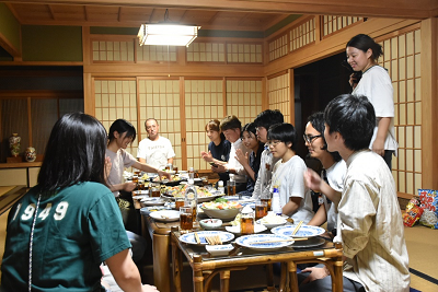 机に並べられた料理を前に笑っている人たちの写真