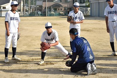 グローブをつけて守備を教わる野球部員の写真