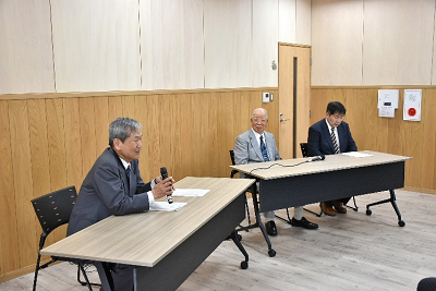 座って話すスーツ姿の男性と話を聞く2人の男性の写真