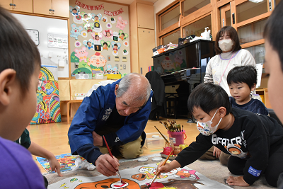 色塗り体験をする園児たちと男性の写真