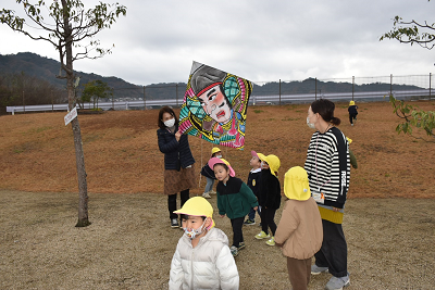 凧あげをする園児たちと先生の写真