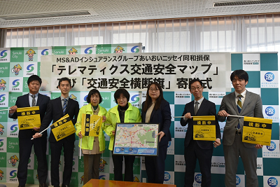 男性4人と女性3人が交通安全マップと交通安全横断旗を持っている写真