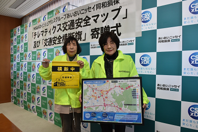 女性2人が交通安全マップと交通安全横断旗を持っている写真