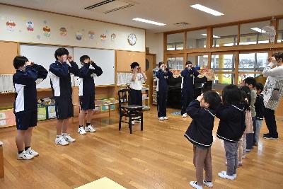 手遊びで遊ぶ複数人の生徒と園児
