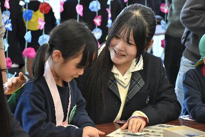 高校生にアサガオの折り方を教わる園児