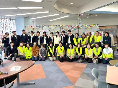 パネル展示の前で記念撮影をする生徒と交通安全母の会のメンバー