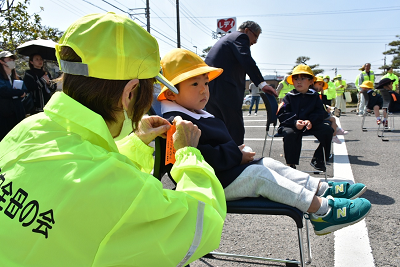 鈴付きリボンをつける女性と男子児童