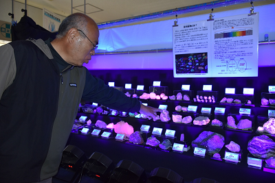 蛍光鉱物を集めたコーナーを解説する男性