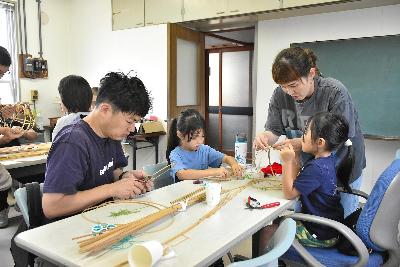 親子4人で協力して竹ひごを円形に整える様子