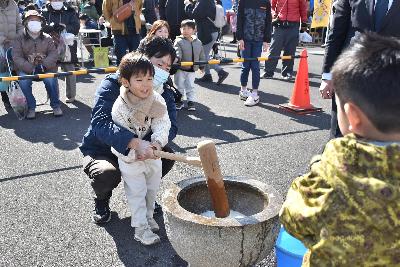 親子で同じ杵をもってもちつきする様子