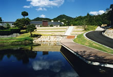 カーブを描く道路のそばに池と建物がある写真